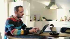 stock-footage-young-man-working-on-laptop-and-drinking-coffee-in-home
